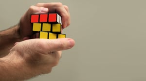 male’s hands trying to solve a rubix cube