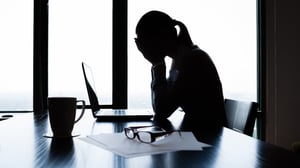 stressed girl with hands over her face and head down at her desk