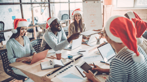 People sitting at office desks wearing Santa hats.